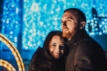 Happy couple in love with christmas lights behind