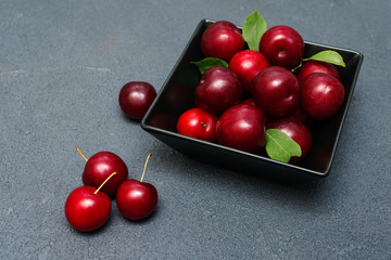 fresh violet plums in black plate on dark  background