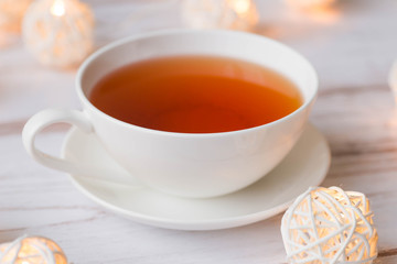 Cup of black tea and Christmas garlands glow