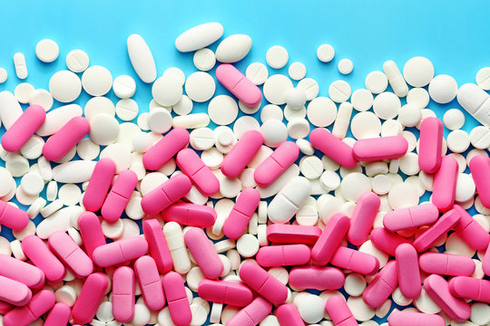White and pink medicine pills on a blue