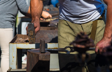blacksmith performs the forging of hot glowing metal on the anvil