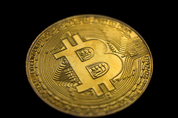 Golden bitcoin (physical), macro shot, isolated on black background