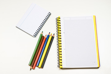 Sensual sketchbook and crayons on a white table. White table and white background.