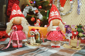 Christmas toy doll with wooden sleigh on which sits a toy dog on a background of Christmas lights.