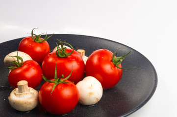 fresh tomatoes and mushrooms - champignons on black plate