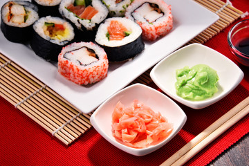 Composition with assorted sushi rolls and bowls of spices
