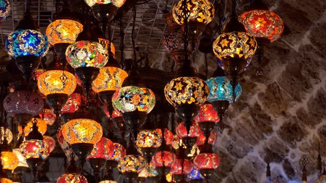 Zoom in to many colourful colorful arabic style lights hanging under the stone ceiling 