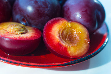 fresh plum fruit in the red saucer on white background