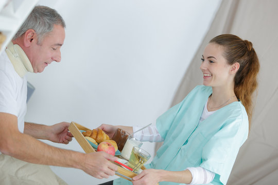 happy nurse giving food to senior man at home