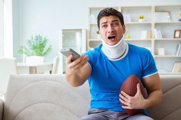 Man with neck injury watching american football at home