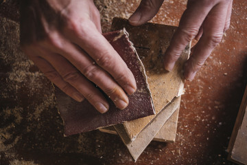 Amateur carpenter uses sandedpaper on wood
