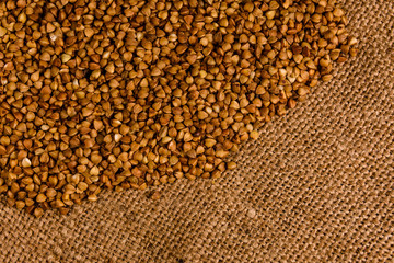 Pile of the raw buckwheat on sackcloth. Top view