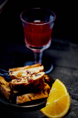 Cookie biscotti on a dark background. A glass of red wine or mulled wine.