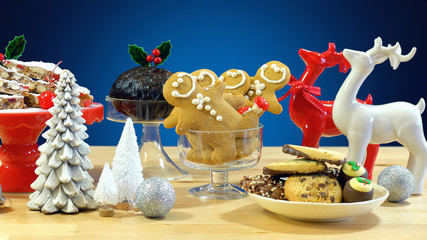 Festive table with traditional English and European style Christmas food including panforte cake, plum pudding, gingerbread cookies, and chocolate covered shortbread.  