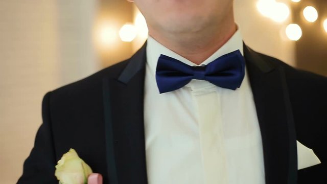 Dressing man straightens bow-tie shallow depth of field