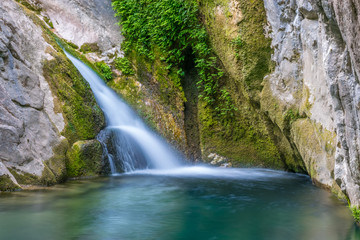 Obraz na płótnie Canvas A small picturesque waterfall in a cozy mountain lagoon.