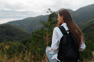 Naklejka premium Young girl with a backpack against the background of mountains.