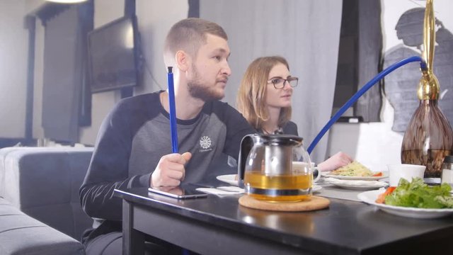 Happy group of friends chatting having drinks tea in coffee shop and smoking hookah