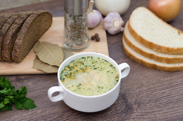 Mushroom soup with croutons in a white dish is on a wooden table.
