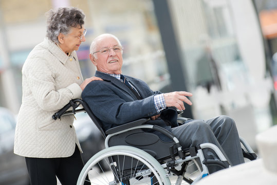 man on wheelchair with optimistic wife outdoors