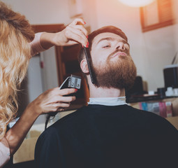 Master cuts hair and beard of men, hairdresser makes hairstyle for a young man. Hipsters
