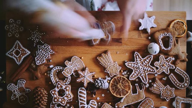Woman Decorating Baked Gingerbread Christmas Cookies, Top View. 4K TIME LAPSE.  Female hands frosting and icing fresh holiday bakery. Festive food, family, Christmas and New Year traditions concept.