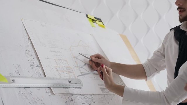 Close-up of two architects discussing a project to build a new project depicted drawings of which are depicted on a large table design