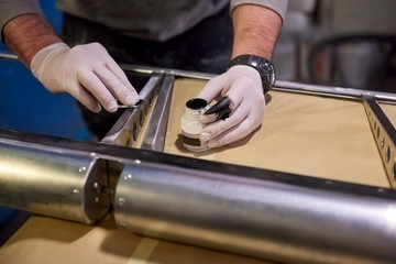 Hands of worker priming metal. Steel and primer. Anti rust coating.