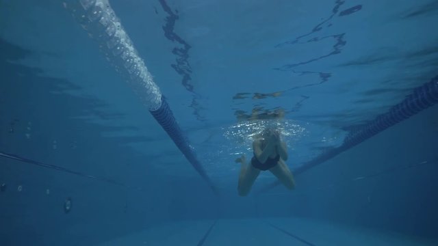 Young woman swimming breaststroke in swimming pool underwater view