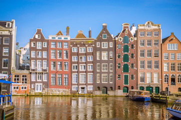 Fototapeta na wymiar Traditional old buildings and and boats in Amsterdam, Netherlands. Canals of Amsterdam.
