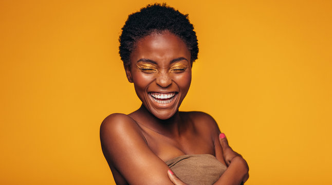 African woman laughing against yellow background