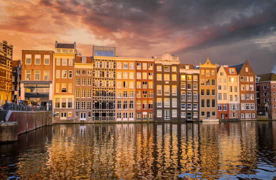 Traditional old buildings and boats at sunset in Amsterdam, Netherlands.