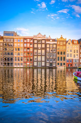 Naklejka premium Traditional old buildings and boats at sunset in Amsterdam, Netherlands.