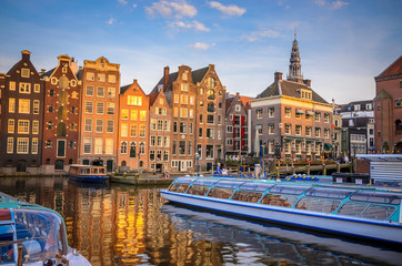 Traditional old buildings and boats at sunset in Amsterdam, Netherlands.
