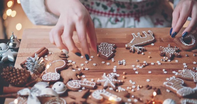 Woman Decorating Baked Gingerbread Christmas Cookies. 4K SLOW MOTION.  Female hands frosting and icing fresh holiday bakery. Festive food, family, Christmas and New Year traditions concept.
