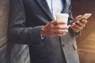 businessman hand holding morning coffee and reading phone