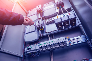 Electricians hands testing switches in electric box. Electrical panel with fuses and contactors
