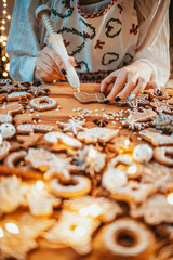 Woman Decorating Baked Gingerbread Christmas Cookies. 4K SLOW MOTION.  Female hands frosting and icing fresh holiday bakery. Festive food, family, Christmas and New Year traditions concept.
