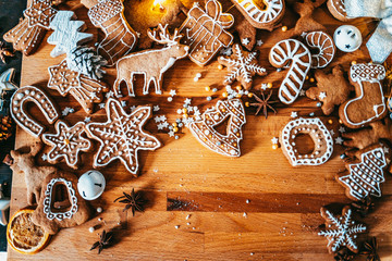 Freshly baked and homemade gingerbread cookies and food decorations on wooden table, flat lay view from above. Christmas handmade bakery. Family festive culinary and New Year traditions concept.