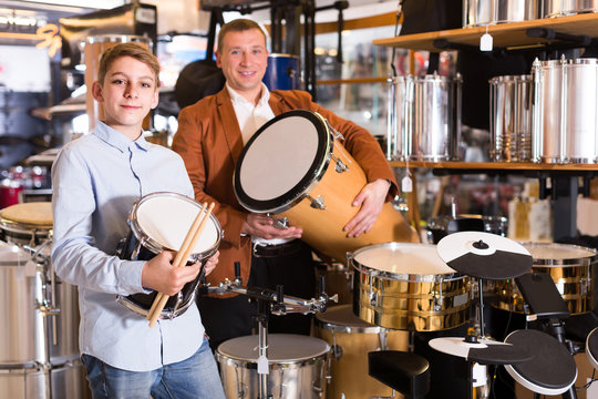 Father and teenage son examining drum units in guitar shop