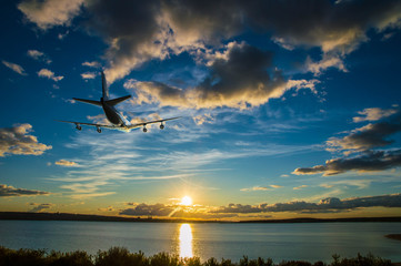 The airplane climbs, flying over the sea towards the sun at sunset