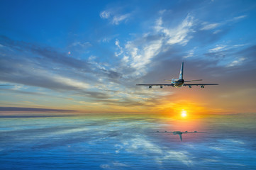 Fototapeta na wymiar The airplane climbs, flying over the sea towards the sun at sunset