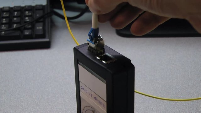 IT engineer insert optical patch cord in tested device.