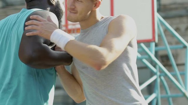 Two friends greeting each other making cool handshake before basketball game