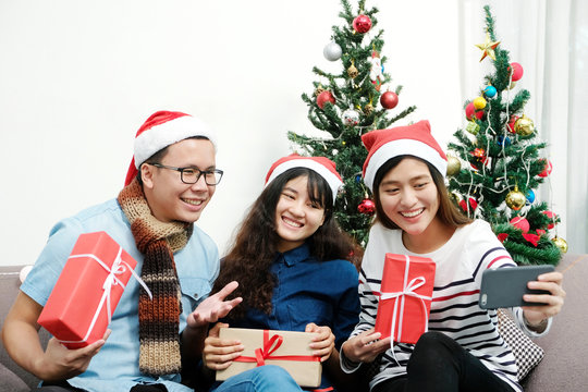 Young asia man and women holding gift boxes taking photo with happiness in Christmas party, friends Christmas party celebration