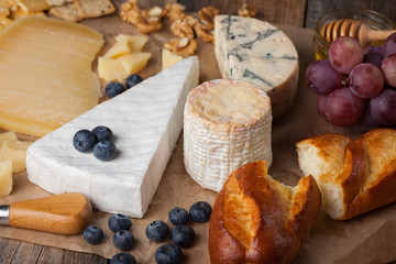 Tasting cheese dish. Food for wine and romantic, cheese delicatessen on a wooden rustic table