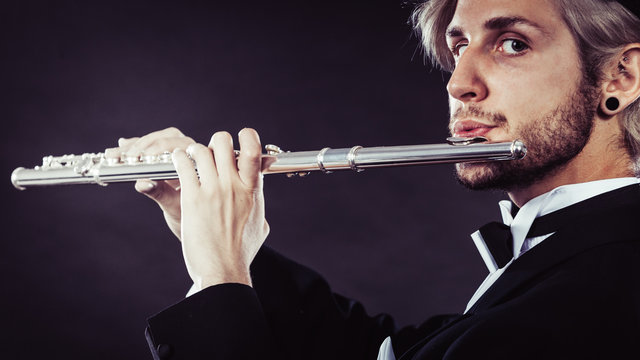 Elegantly dressed male musician playing flute