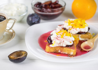 Half the plums next to a plate with toasted French bread.