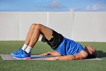 Fitness man doing bodyweight glute floor bridge pose yoga exercise. Fit athlete exercising glutes...