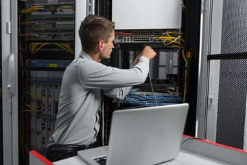 Young business man with laptop working in data center